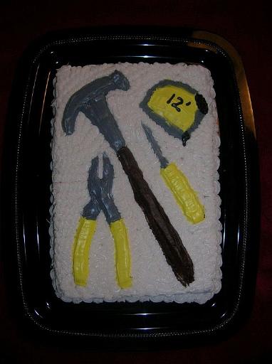 Tool Cake.JPG - For a woodworker's or handyman's birthday, make a tool cake. Press a 3/4-inch layer of clay into the bottom of 13x9-inch pan, and lightly coat the clay with powdered sugar. Place a sheet of plastic wrap over the clay. Place a real tool on top of the plastic wrap, and firmly press it into the clay, using a rocking motion. Repeat for the other tools. Remove the plastic wrap and smooth any bumps that may have formed around the edges of the tool shapes. Spray the pan and clay with cooking spray, and pour cake batter such that the batter is about 3/4-inch above the highest portion of the clay. Bake until done, loosen the cake from the sides of the pan, and invert the pan.Added by: Admin.